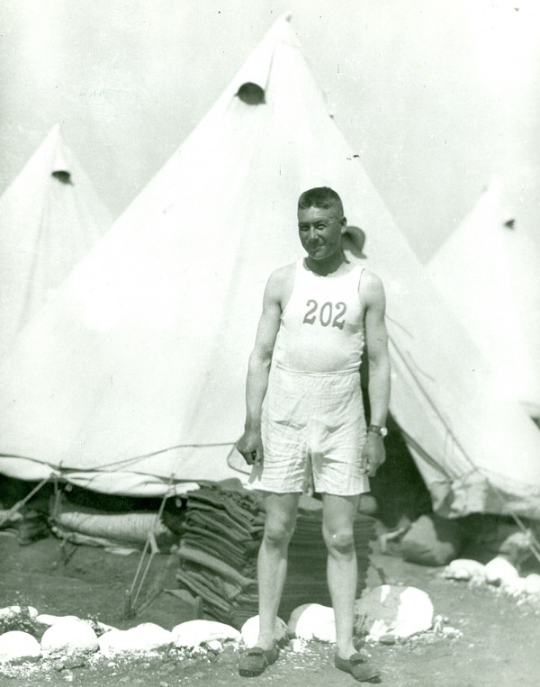 Photograph of Alex Decoteau standing in front of tent
