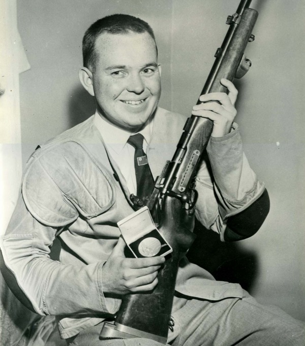 Photograph of Gerry Ouellette holding a rifle and medal