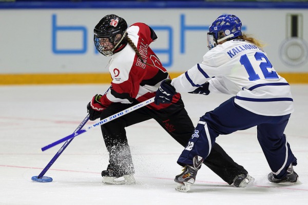 Photograph of two ringette players with sticks and plastic ring
