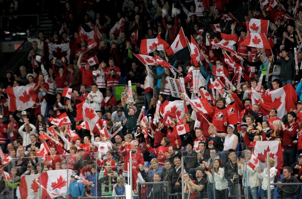 photograph of spectators waving Canadian flag at hockey game