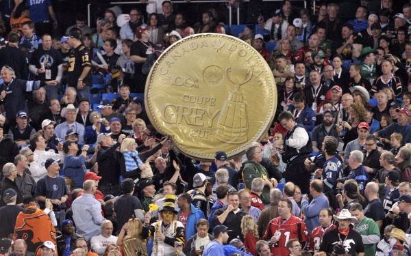 fans hold homemade copy of the Grey Cup Loonie