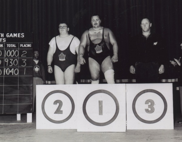 Photograph of winners standing behind podium, Doug Hepburn at centre