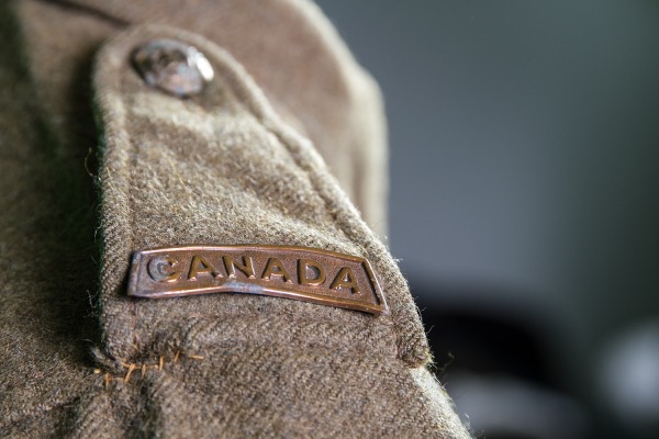 Military metal shoulder badge that reads CANADA