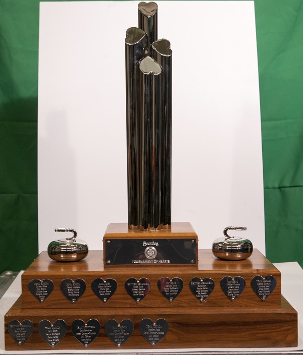 Scotties trophy with four plinths, two curling rocks, and heart shaped engraved silver plaques.