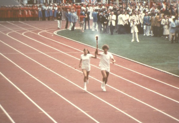 two torchbearers running in the Olympic stadium with torch