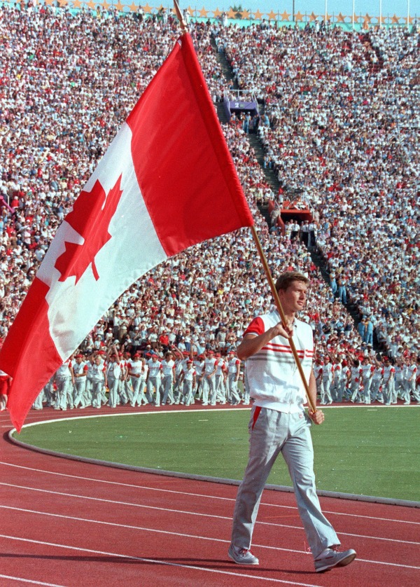 photograph of Alex Baumann carrying Canadian flag