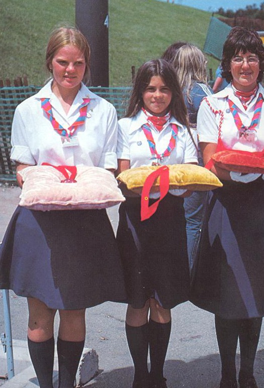 photograph of three girls in uniform holding medals on cushions
