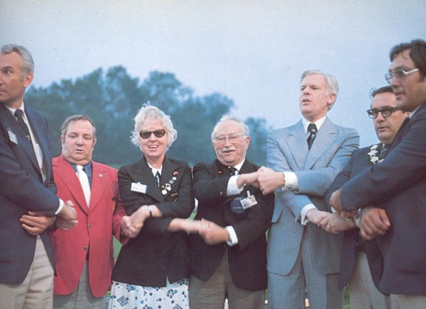 photograph of group of seven individuals holding hands)